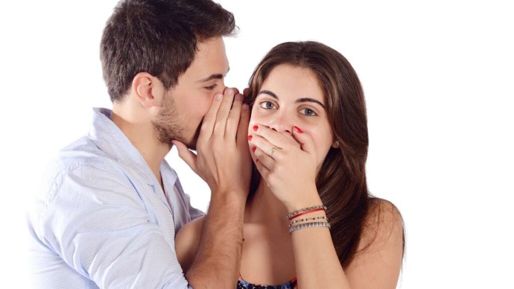 Sakarya diş kliniğinde uygulanan ağız kokusu (halitosis) tedavisi sonrası, sosyal ortamlarda ve yakın ilişkilerde özgüvenle iletişim kuran, kulağına fısıldayan mutlu çift.